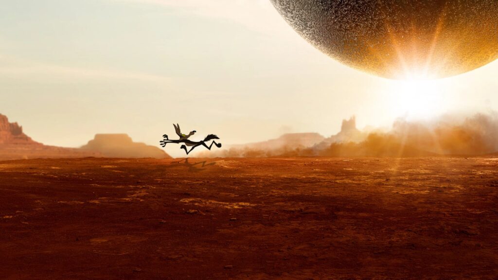 A stylized desert landscape at sunset with a small cartoon bird running across the center as a huge glowing boulder hangs overhead.