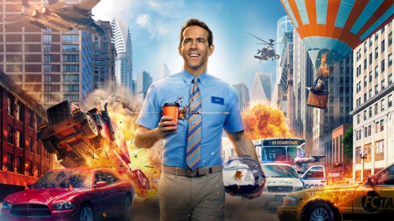 A smiling man in a blue bank-worker uniform holds a coffee and a fishbowl in a city street as explosions, overturned vehicles, police cars, a helicopter, and a suspended platform create chaos around him.